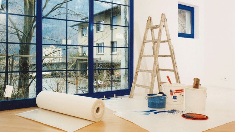 Auslegung eines weißen Schutzvlieses bei Malerarbeiten in Wohnung